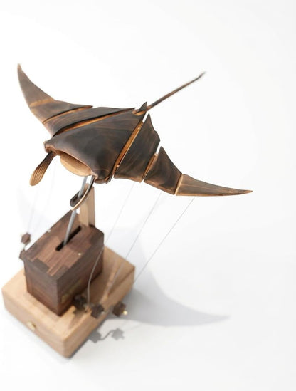 Handcrafted walnut wooden kinetic manta ray sculpture with wave motion on a desk